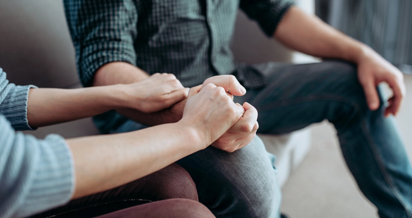 Two people sitting together and holding hands.